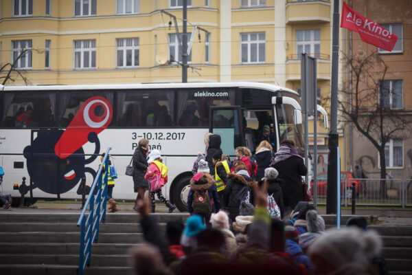 W tle autokar AleKino! przed którym czeka grupa dzieci i dorosłych.