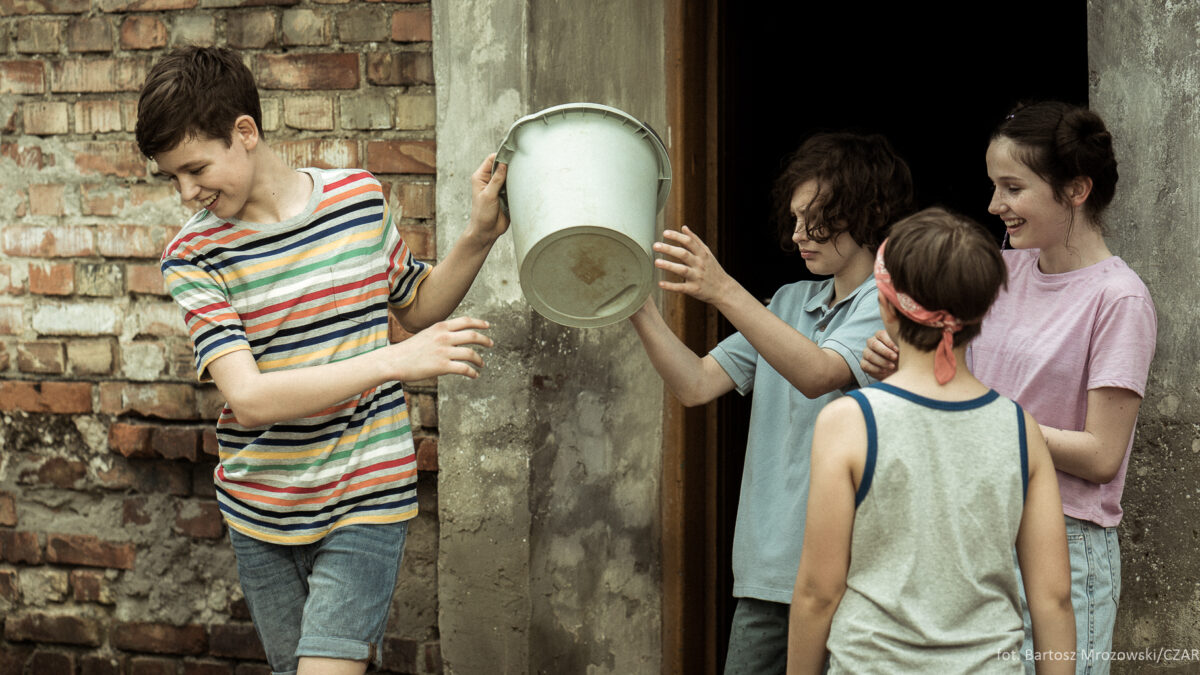 Chłopiec daje plastikowe wiadro innym dzieciom
