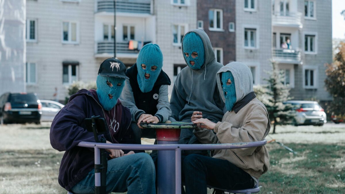 czwórka nastolatków  wniebieskich kominiarkach na karuzeli