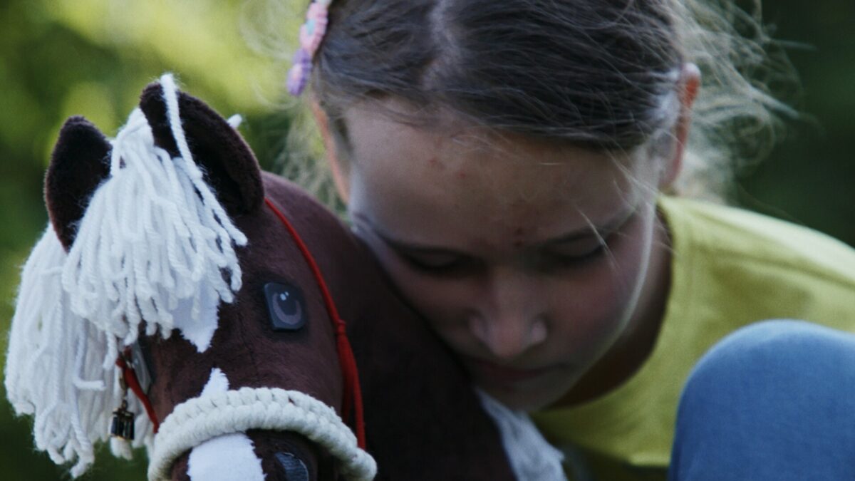 dziewczynka przytula zabawkowego konika