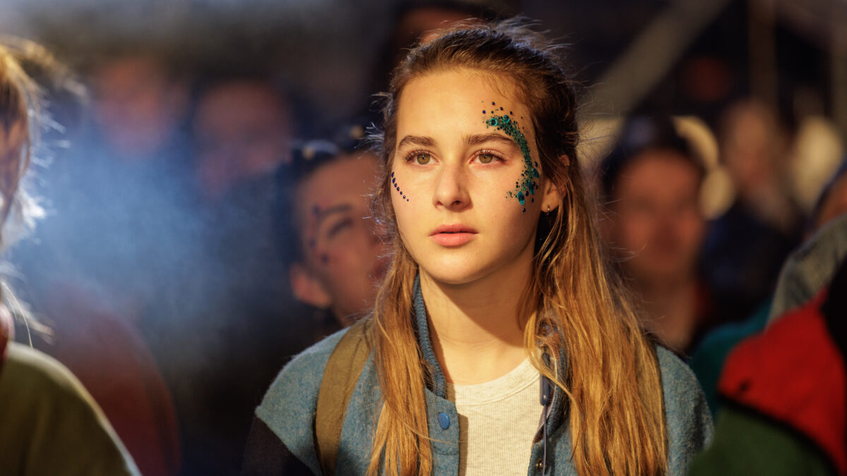 dziewczyna z błyszczącymi plamkami na twarzy stoi na imprezie