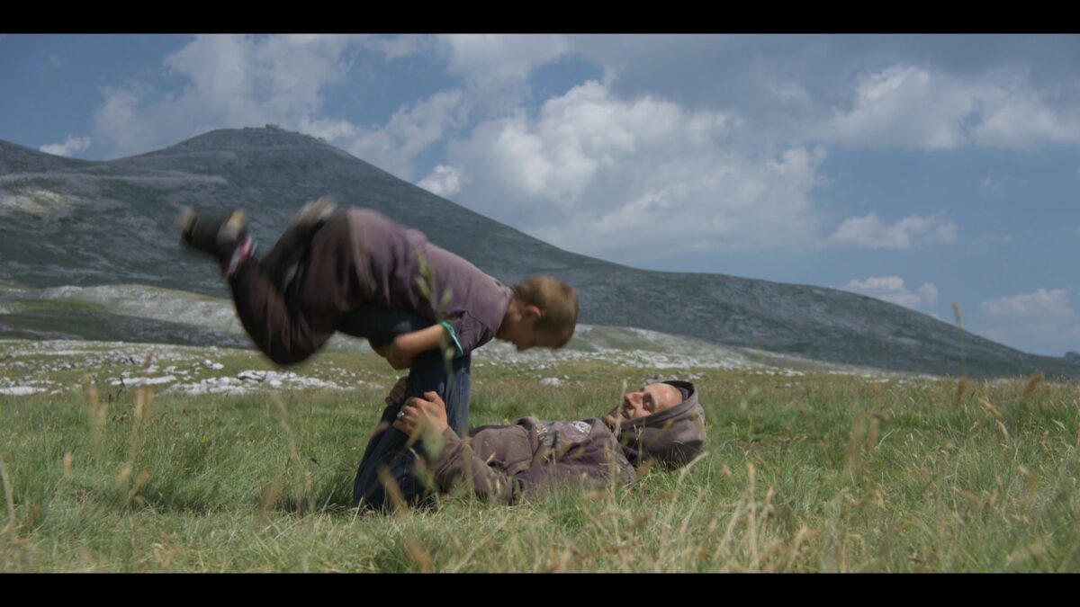 Mężczyzna bawi się z małym chłopcem na łące