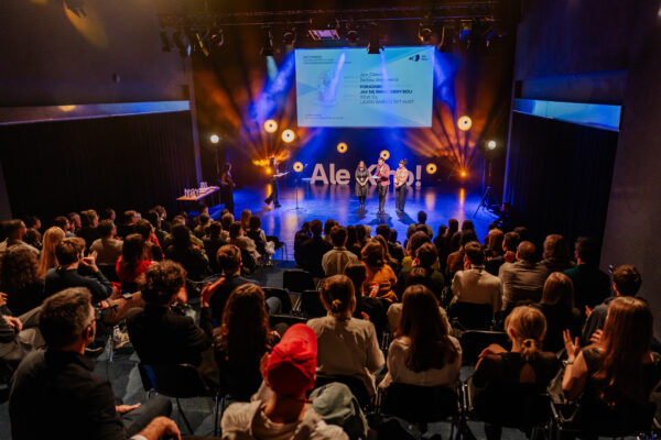 pełna sala publiczności w tle na scenie napis Ale Kino! i ekran