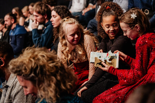 trzy małe dziewczynki siedzą na publiczności z nagrodą