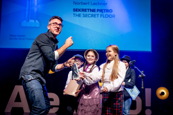 mężczyzna i czwórka dzieci na scenie, która wręcza mężczyźnie nagrodę