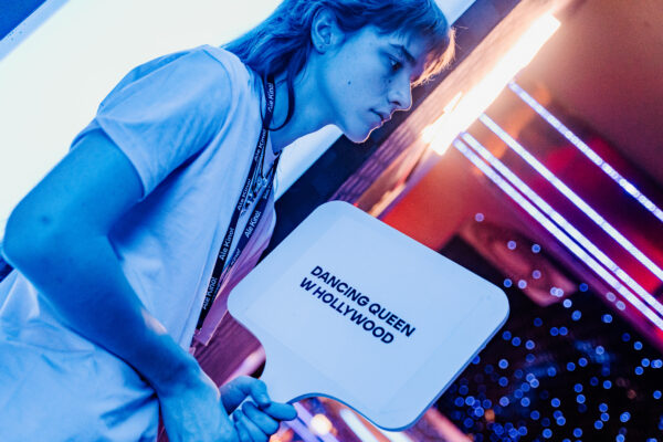 młoda osoba z tabliczką z tytułem filmu Dancing Queen w Hollywood