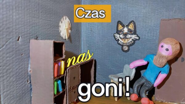 Kadr z filmu animowanego, plastelinowa postać siedzi na krześle w pokoju z kartonowymi meblami, na ścianie wisi zegar i ilustracja kota, a na ekranie widoczny jest napis „Czas nas goni!”.