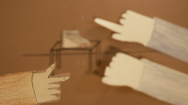 Kadr z filmu animowanego, kilka rysunkowych dłoni wyciąga się w stronę stołu ustawionego w centrum sceny.