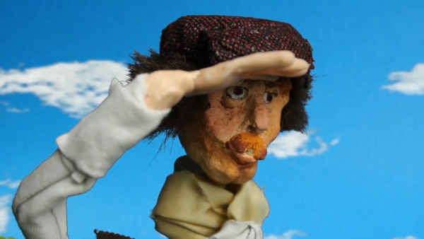 Kadr z filmu animowanego, lalka przedstawiająca mężczyznę w czapce zasłania oczy dłonią, patrząc w dal na tle nieba.