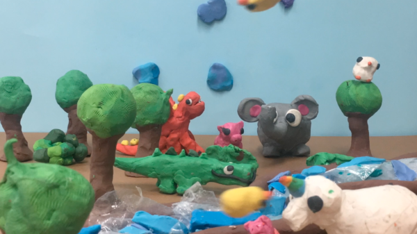 Kadr z filmu animowanego, plastelinowe zwierzęta znajdują się wśród drzew i roślin w bajkowym krajobrazie.
