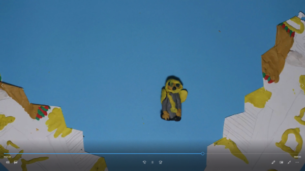 Kadr z filmu animowanego, mała postać stoi pośrodku przestrzeni między dwoma zboczami na tle nieba.