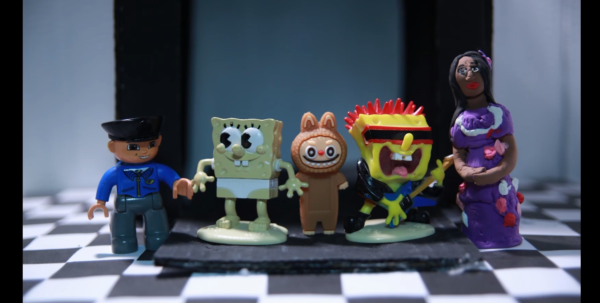 Kadr z filmu animowanego, kilka małych figurek i postaci stoi obok siebie na podłodze w pomieszczeniu o czarno-białej, szachownicowej posadzce.