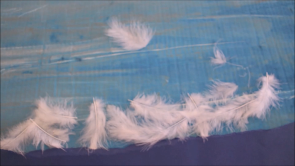Kadr z filmu animowanego, kilka białych piór unosi się na niebieskim tle przypominającym niebo lub wodę.