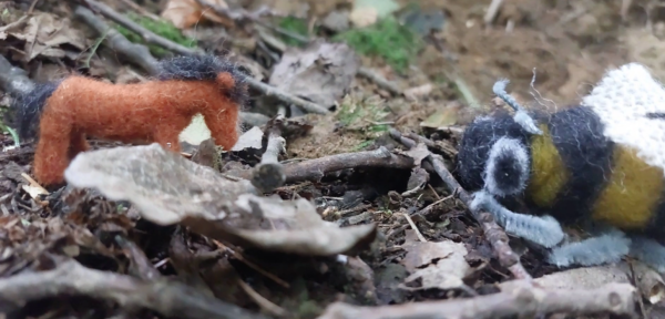 Kadr z filmu animowanego, małe filcowe zwierzęta znajdują się na leśnej ściółce wśród liści, gałązek i ziemi.