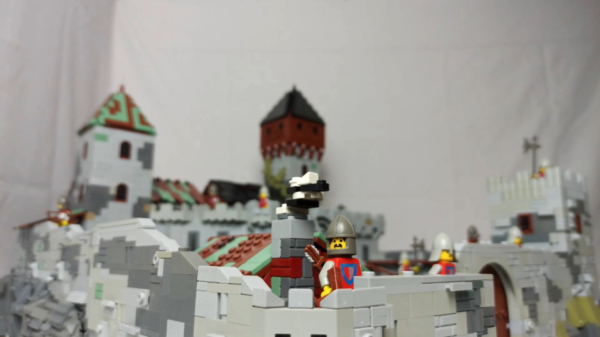 Kadr z filmu animowanego, makieta zamku zbudowana z klocków przedstawia mury obronne, wieże oraz figurki rycerzy stojących na murach