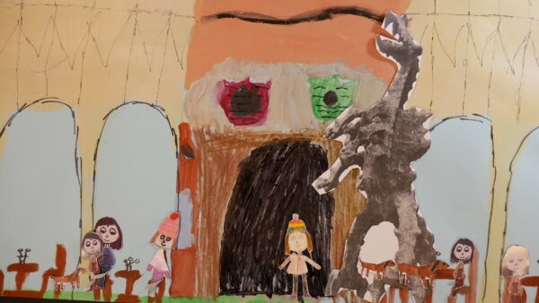 Kadr z filmu animowanego przedstawia scenę z papierowymi postaciami i dużą konstrukcją przypominającą budynek.