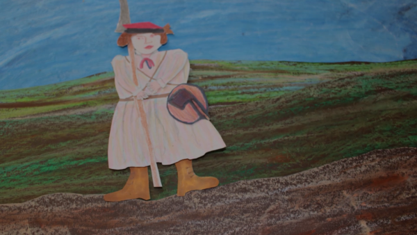 Kadr z filmu animowanego, papierowa postać dziecka w czerwonej czapce idzie przez pagórkowaty krajobraz w kierunku domu.