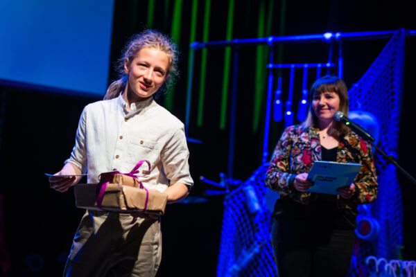 chłopak pozuje na scenie z nagrodą