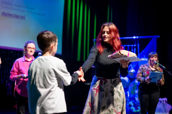 kobieta wręcza nagrodę chłopcu i ściska jego dłoń