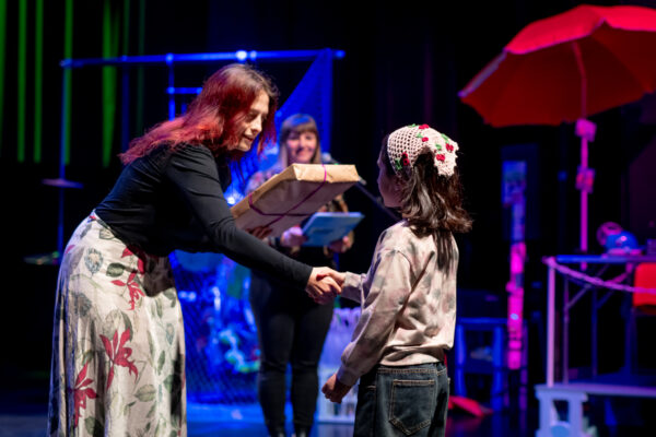 Kobieta wręcza nagrodę dziewczynce na scenie