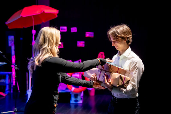 chłopak odbiera z rąk kobiety nagrodę